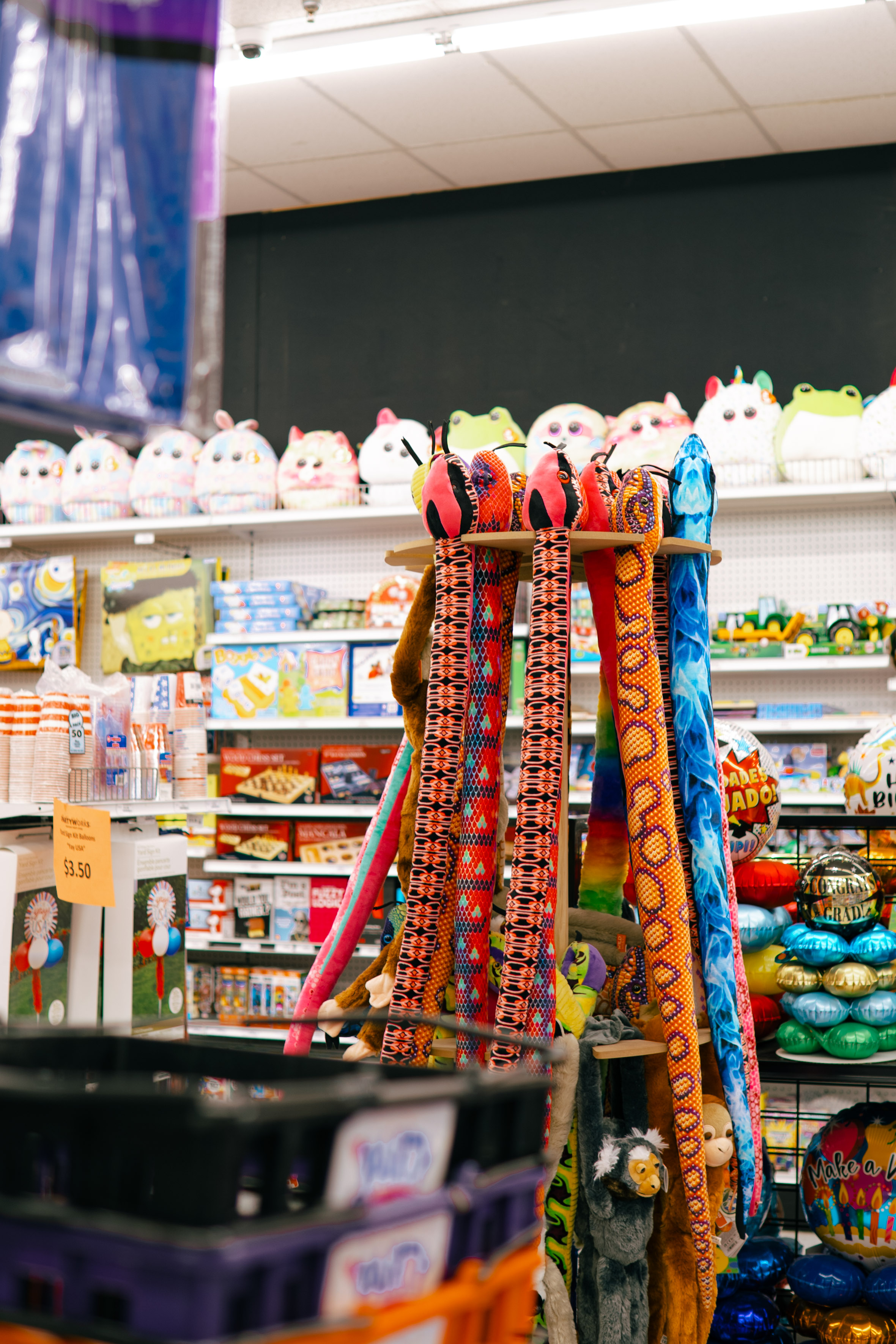 Rotating plush snake display tower surrounded by classic board games and toys